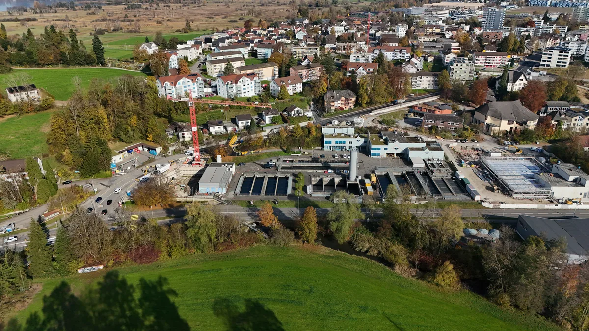 Man sieht eine Drohnenaufnahme einer Strasse und einer Abwasserreinigungsanlage. 